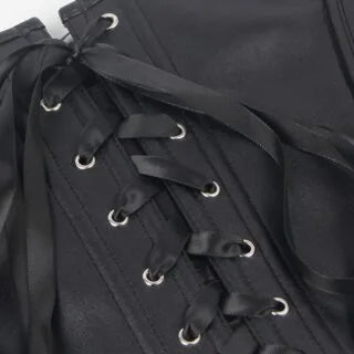 Close-up of the lace-up back detail on a black faux leather corset, featuring structured seams and satin ribbons.